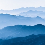 layers of mountains in shades of blue with clouds