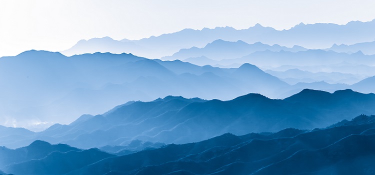 layers of mountains in shades of blue with clouds